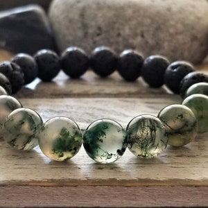 Peut inclure: Un bracelet élastique composé de perles rondes en pierre de lave noire poreuse et de perles en agate mousse translucide et lisse. Les perles en agate mousse présentent des inclusions vertes naturelles rappelant le feuillage, avec une texture mate.