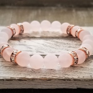 May include: A pink rose quartz bracelet with rose gold accents and clear crystal accents.