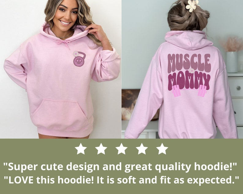 May include: Pink hoodie with a kettlebell graphic on the front and "MUSCLE MOMMY" text on the back. The hoodie has a drawstring hood and a kangaroo pocket.