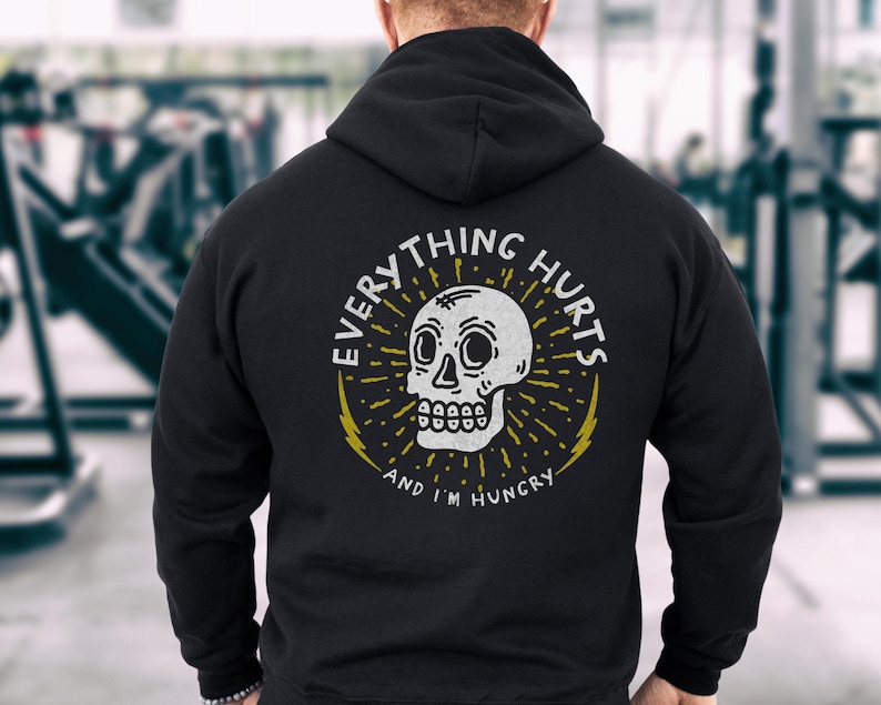 May include: Black hooded sweatshirt with a white skull graphic and the text "Everything Hurts and I'm Hungry".