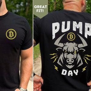 May include: Black t-shirt with a gold Bitcoin logo on the front and a graphic of a bull with the text "PUMP DAY" on the back.
