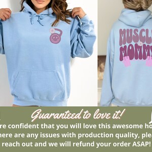 May include: Light blue hoodie with a pink and purple "Muscle Mommy" graphic on the back and a pink and purple kettlebell with a flower on the front.