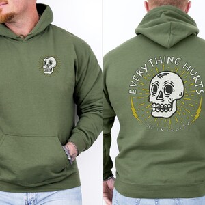 May include: A green hooded sweatshirt with a skull graphic and the text "EVERYTHING HURTS AND I'M HUNGRY".