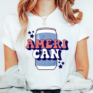 May include: White t-shirt with a retro-style graphic of a blue and white can with the text "AMERI CAN" in red, white, and blue.