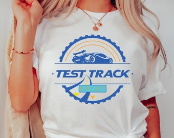 May include: White t-shirt with a blue and yellow graphic of a race car on a track with the text "Test Track. Epcot."