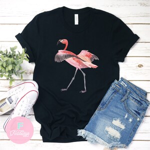 May include: Black t-shirt with a pink flamingo illustration. The flamingo is standing on one leg with its wings spread out.