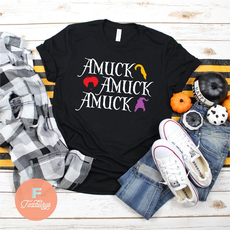 Puede incluir: Camiseta negra con texto blanco que dice "AmuCK AmuCK AmuCK" con un gr&aacute;fico de bruja, coraz&oacute;n y sombrero de bruja.