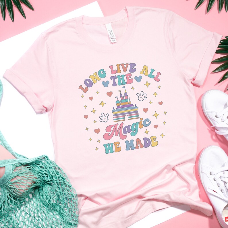 May include: Pink t-shirt with a colorful graphic of a castle and the text "Long Live All The Magic We Made".