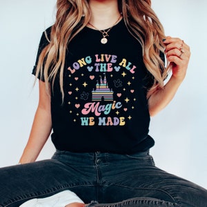 May include: Black t-shirt with a colorful graphic design featuring a castle, hearts, stars, and the text "Long Live All The Magic We Made".