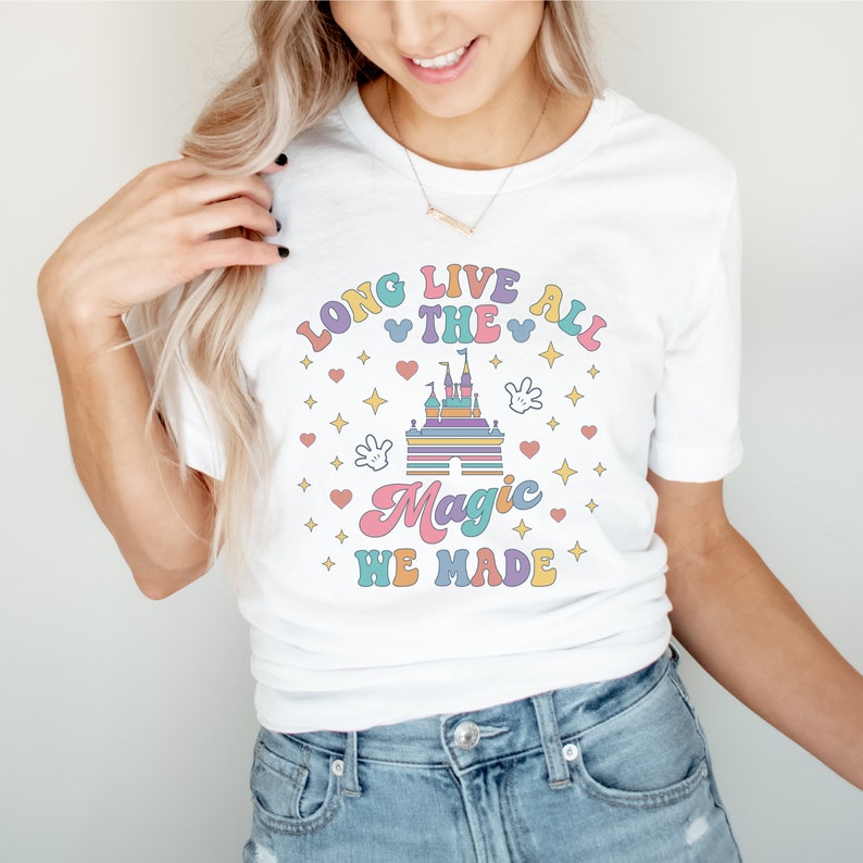 May include: White t-shirt with a colorful graphic design featuring a castle, stars, hearts, and the text "Long Live All The Magic We Made".