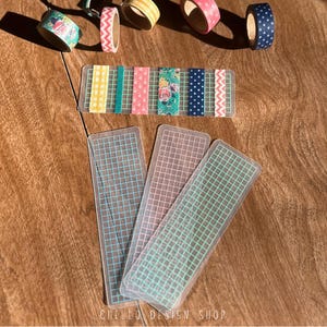 Peut inclure: Ensemble de rubans adh&eacute;sifs washi d&eacute;coratifs et de marque-pages &agrave; motifs quadrill&eacute;s. Les rubans pr&eacute;sentent divers motifs, notamment floraux, &agrave; pois et en zigzag, dans des couleurs comme le rose, le bleu et le jaune. Les marque-pages ont un motif quadrill&eacute;.