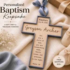 May include: A wooden cross-shaped baptism keepsake with the name "Greyson Archer" and the date "July 26, 2026" engraved. The cross includes a blue ribbon for hanging and the text "You are a child of God..." and "Psalm 139".