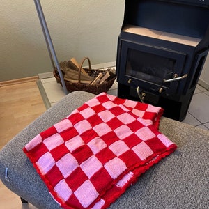 Könnte beinhalten: Ein gestricktes Oberteil mit pinkfarbenen und roten Karos und einer gehäkelten Kante.