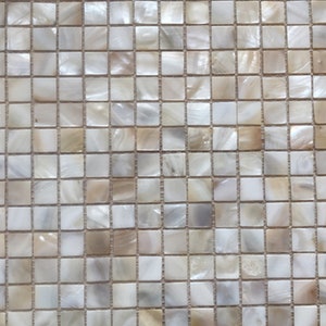 Op de afbeelding: Een vel wit en beige iriserende parelmoer tegelmozaïek. De tegels zijn kleine vierkanten die in een rasterpatroon zijn gerangschikt.