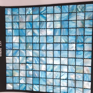 May include: A mosaic tile sheet featuring small, square tiles in shades of blue and white. The tiles have a pearlescent, swirling pattern, creating a water-like effect. The tiles are arranged in a grid pattern, suitable for various design applications.