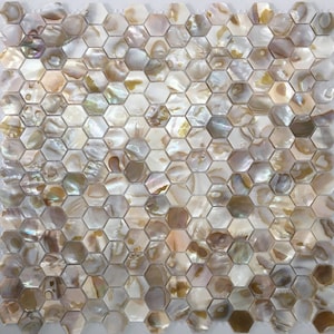 以下が含まれることがあります： 真珠貝で作られた、虹色の白と金の六角形のモザイクタイルのシートです。