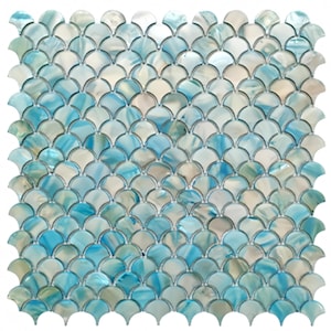 May include: A square mosaic tile sheet with a fan-shaped tile pattern. The tiles are a blend of light blue, white, and pearlescent hues, producing a shimmering appearance. The design is reminiscent of fish scales.