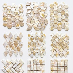 Puede incluir: Nueve pequeñas muestras de mosaicos iridiscentes en varios patrones geométricos. Los azulejos son principalmente blancos y beige, con un brillo nacarado. El texto "USD 29.99/Pack of 9 Small Samples" es visible en la parte superior.