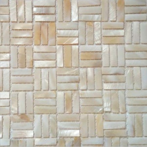 May include: Close-up of a mosaic tile pattern. The tiles are rectangular and arranged in a brick-like pattern. The tiles have a pearlescent, off-white colour with subtle variations of beige and cream.