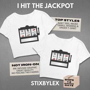 May include: Two white short-sleeved t-shirts featuring a black slot machine graphic. The left shirt displays the word little, while the right shirt displays the word big. Each slot machine graphic includes icons of a star, boot, cherry, lips, horse, and an 8-ball.