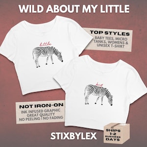 May include: Two white crop tops with zebra illustrations. One top has the word "little" above the zebra, and the other has "big". The tops are labeled "Baby Tees, Micro Tanks, Womens & Unisex T-Shirt". The text "Wild About My Little" is at the top.
