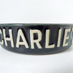 May include: A black ceramic pet bowl with white lettering that reads "CHARLIE'S".