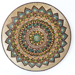 Pode incluir: Um prato decorativo redondo com fundo prateado e um design floral colorido. O design apresenta um padrão de mandala com flores azuis, verdes, laranja e rosa.