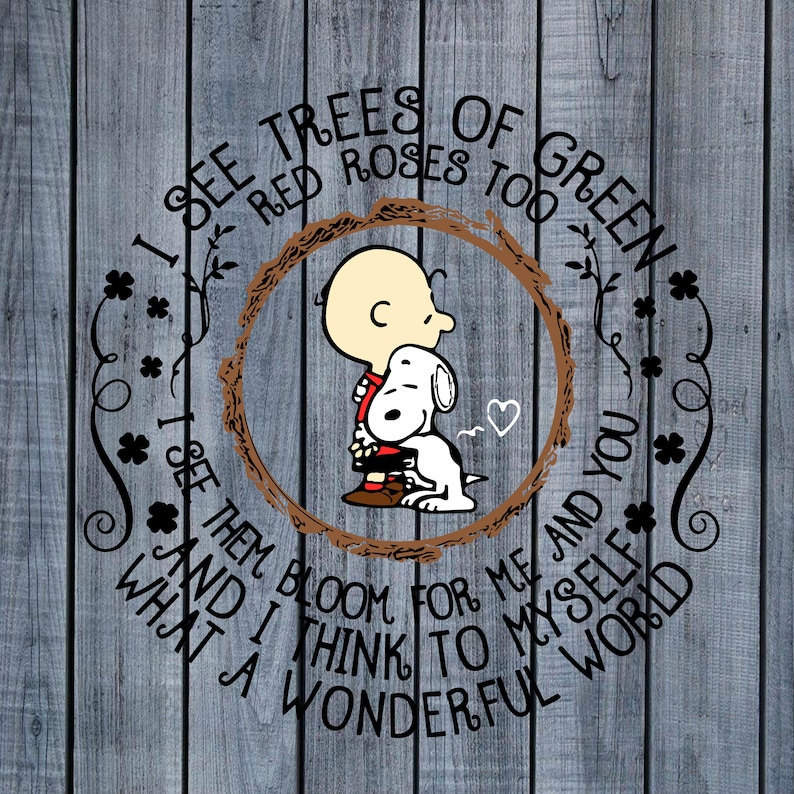 May include: A circular design featuring Charlie Brown hugging Snoopy, surrounded by a brown wreath and floral accents. The text reads "I see trees of green, red roses too... What a wonderful world." The background is a weathered, gray wooden surface.
