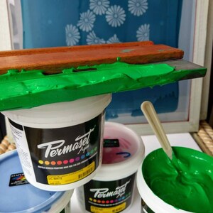 May include: Four containers of green, blue, pink, and white screen printing ink. The containers are labeled "Permaset Aqua" and "SIC White".