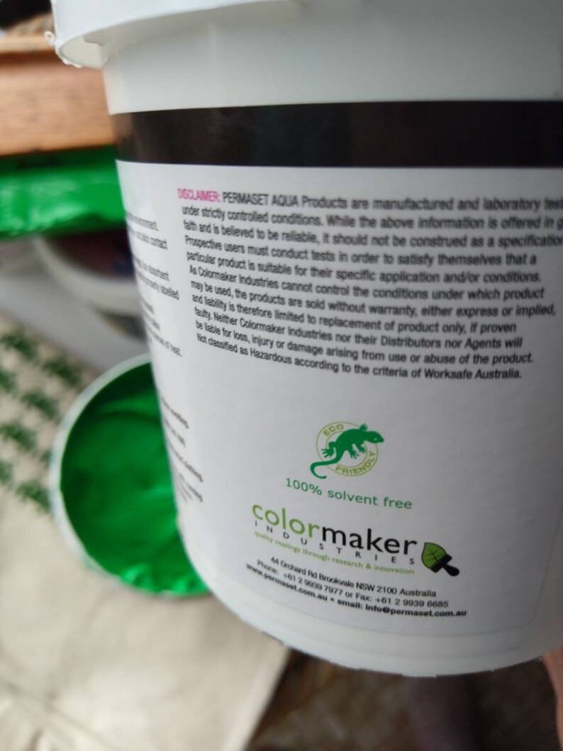 Może przedstawiać: Białe wiaderko z farbą z zielonym logo jaszczurki i tekstem "100% bez rozpuszczalnik&oacute;w" oraz "colormaker industries" nadrukowanym na etykiecie. Etykieta zawiera r&oacute;wnież adres, numer telefonu, adres e-mail i stronę internetową firmy.
