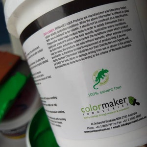 May include: A white bucket with a green lid. The bucket contains green paint. The label on the bucket says "Permaset Aqua Products" and "Colormaker Industries". The label also says "100% solvent free" and "quality coatings through research & innovation".
