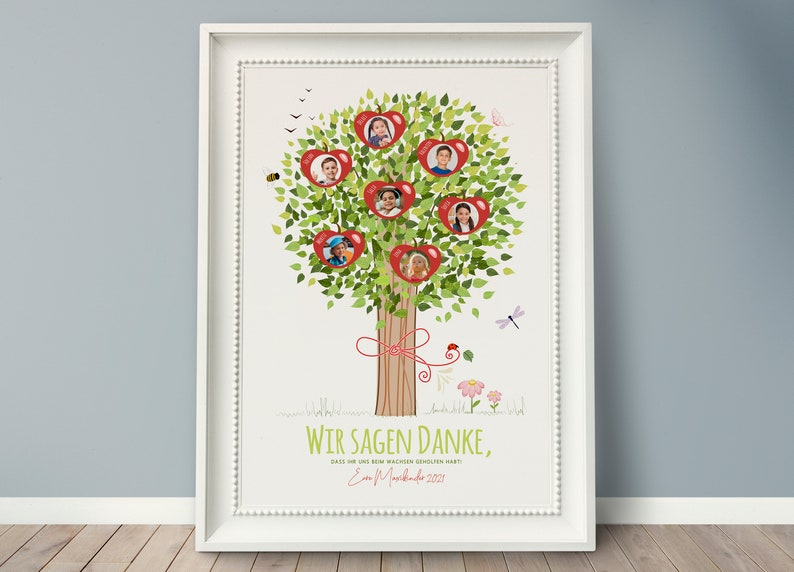 May include: A framed print with a red apple tree with green leaves and photos of children in the apples. The text at the bottom reads "Wir sagen Danke, dass ihr uns ein Jahr wachsen geholfen habt.  Ein wundersch&ouml;ner Herbst 2021."