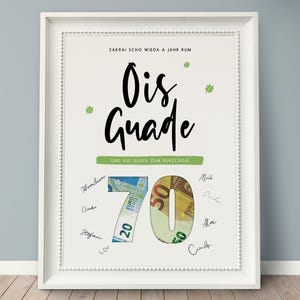 Könnte beinhalten: Gerahmter Druck mit den Worten "Ois Guade" in großer schwarzer Schrift, mit der Zahl 70 aus Euro-Banknoten. Der Druck enthält Unterschriften und grüne Kleeblatt-Akzente, mit Text oben und unten.