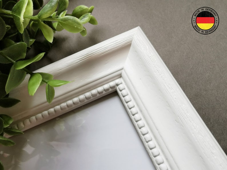 May include: White picture frame with a beaded edge and a white mat. The frame is made in Germany.