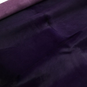 Pode incluir: Um close-up de um tapete de couro de vaca roxo escuro com uma textura macia e aveludada.