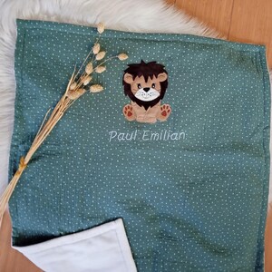Puede incluir: Una manta de bebé verde con lunares blancos y una aplicación de león. La manta está personalizada con el nombre "Paul Emillian".