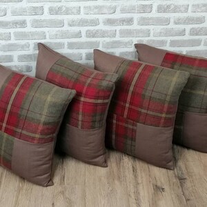 May include: Four brown and red tartan throw cushions with a brown fabric backing. The cushions are arranged in a row on a wooden floor.
