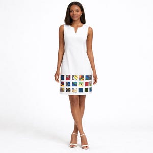 May include: A sleeveless white knee-length dress featuring a notched neckline and a hemline decorated with a grid of colorful, multi-patterned square fabric patches in various shades of blue, yellow, red, green, and black.
