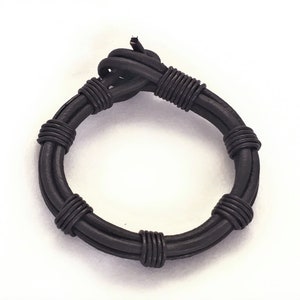 May include: A black leather bracelet with a braided design.