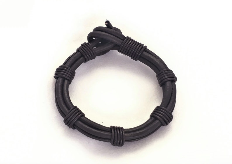 May include: A black leather bracelet with a braided design.