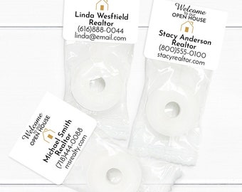 May include: Three clear plastic bags with white round candy inside. Each bag has a small card attached with the text "Welcome to our Open House" and a realtor's name, phone number, and email address.
