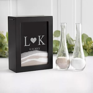 May include: A black wooden box with a glass front, containing two glass bottles filled with sand. The box has a personalized inscription with the initials "L♥K" and the date "8.18.20XX".