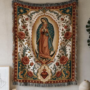 May include: A woven tapestry wall hanging featuring a central image of the Virgin of Guadalupe surrounded by a golden sunburst, red roses, and green foliage. The design includes a sacred heart at the bottom and a decorative border with fringe.