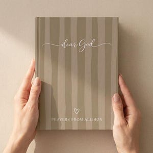 Puede incluir: Un diario de tapa dura con un patrón de rayas verticales en color topo y beige. La portada presenta el texto en cursiva blanca "dear God" en la parte superior, un pequeño icono de corazón blanco en el centro y el texto blanco "PRAYERS FROM ALLISON" en la parte inferior.