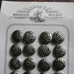 Könnte beinhalten: Eine Karte mit 15 silbernen Knöpfen mit grünem Emaille-Design. Auf der Karte steht "BRUXELLES MODE" gedruckt.