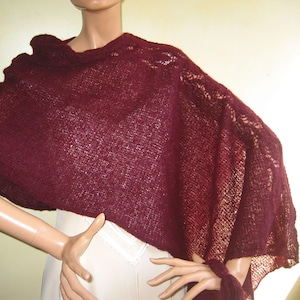 Könnte beinhalten: Ein burgunderfarbener Strick-Schal mit einem zarten Spitzenmuster an den Rändern. Der Schal ist über die Schultern einer Schaufensterpuppe gelegt.