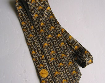 Könnte beinhalten: Eine schwarze und goldene Seidenkrawatte mit einem sich wiederholenden Muster aus kleinen Autos und einem geometrischen Design. Die Krawatte hat ein kleines goldenes Etikett mit dem Wort "Dior" darauf.