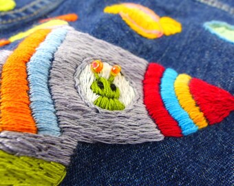 Hand embroidered little alien rocket kid's, boy or girl, denim jean jacket with colorful planets and pocket stitched front.