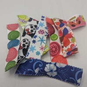 May include: A collection of colorful hair bows with various patterns. Designs include polka dots, panda bears, snowflakes, and floral prints. The bows are made of ribbon and are suitable for various hairstyles.