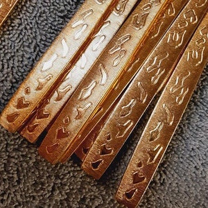 May include: A set of gold-colored silverware with intricate patterns on the handles. The silverware is arranged in a stack, with the handles facing up.